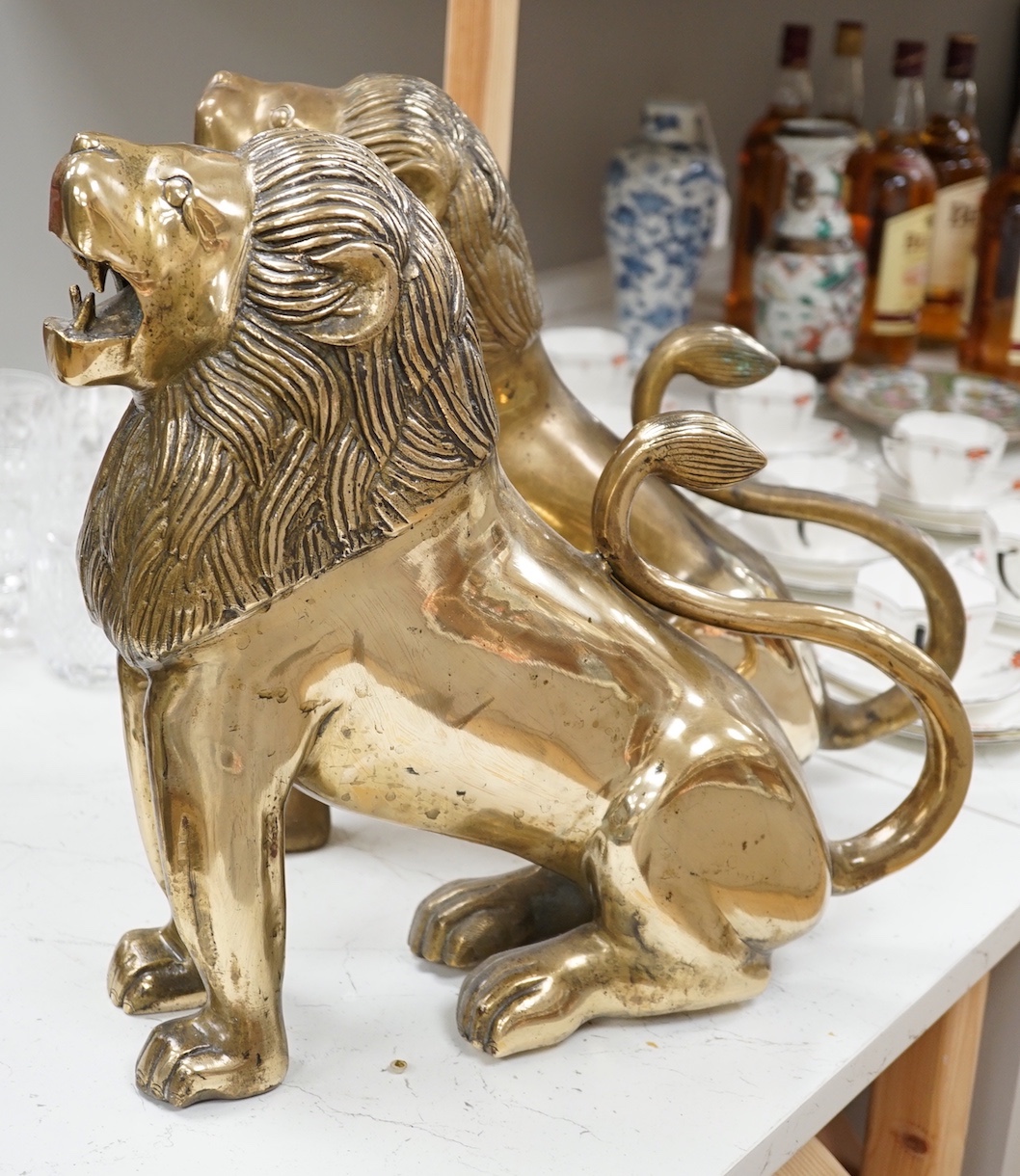 A pair of large brass lion models. 39cm